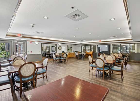 A large room with wooden floors and tables with chairs.