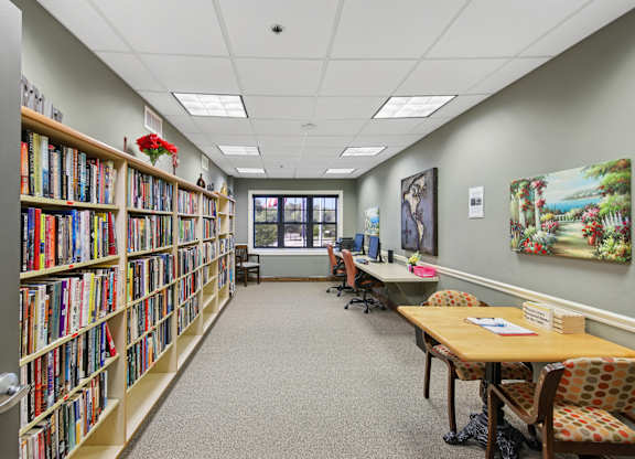 A library with bookshelves, tables, and chairs.