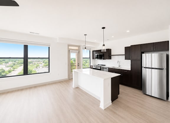 A modern kitchen with a large island and a view of the city.