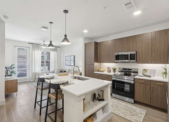 an open kitchen and dining area with a white island and wooden cabinets
