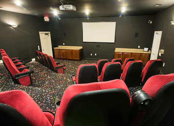 A movie theater with red seats and a white screen.