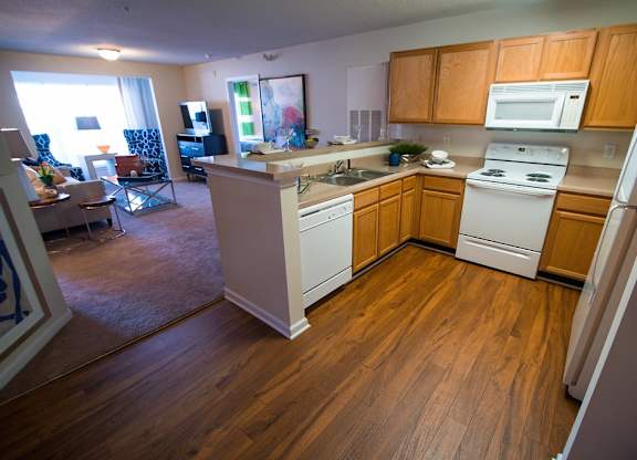 A kitchen with wooden floors and white appliances.