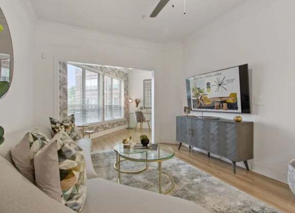 A living room with a grey cabinet, a glass table, and a painting on the wall.