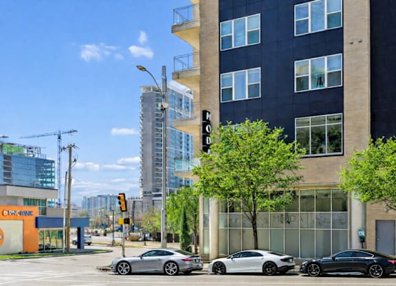 Three cars are parked in front of a building with a glass facade.