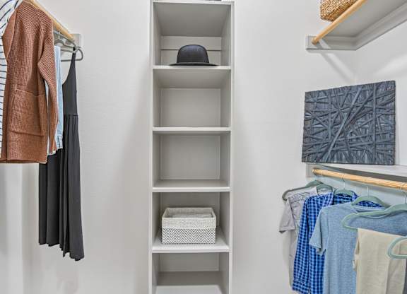 Markethaus 3700 A closet with clothes hanging and shelves with storage boxes.