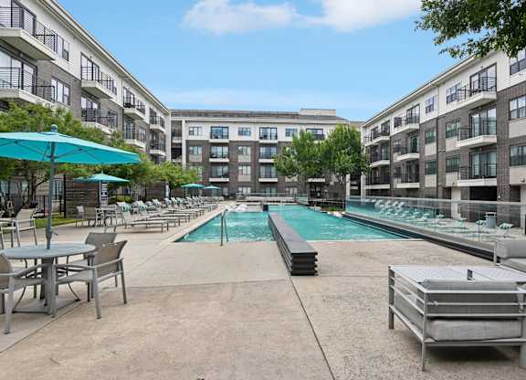 Markethaus 3700 Pool Views from Home A pool area with a table and chairs is surrounded by apartment buildings.
