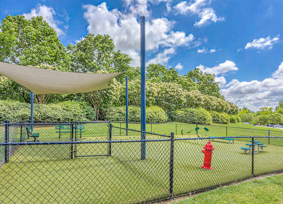 A playground with a green fence and a red fire hydrant.