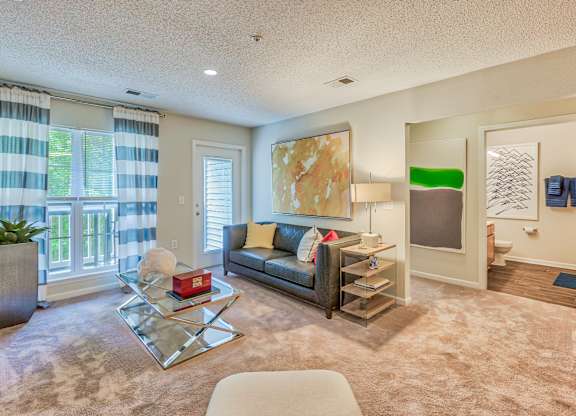 A living room with a couch, coffee table, and a painting on the wall.