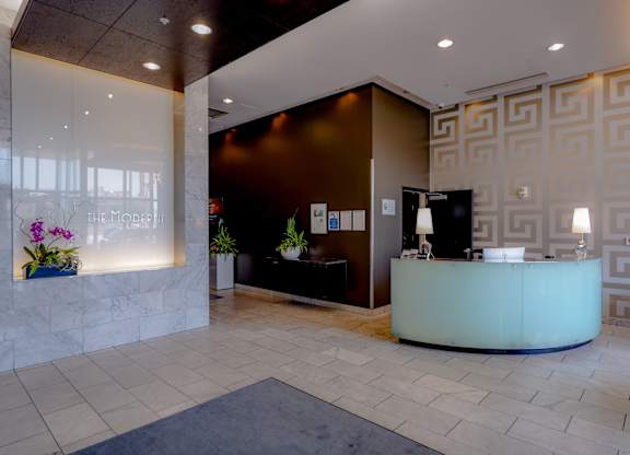 A reception area with a white counter and a black chair.