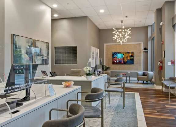 A reception area with a desk, chairs, and a painting on the wall.