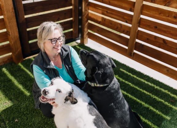 a woman sitting on the grass with two dogs