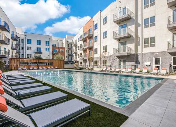 Sparkling resort style swimming pool with cushioned lounge chairs