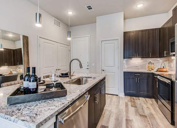 Granite counter tops, stainless appliance package, medium brown cabinets, plank wood-style flooring, island seating, abundant cabinet and pantry space