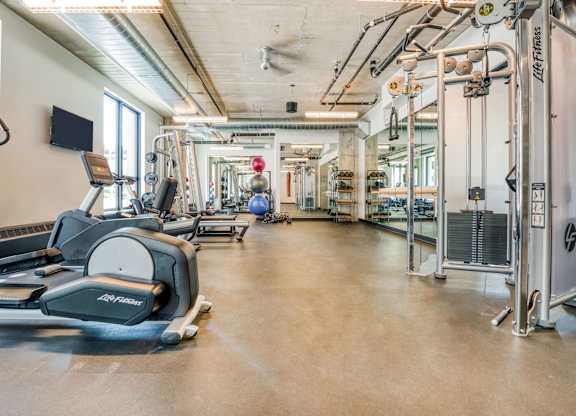 a gym with cardio equipment and weights on the floor