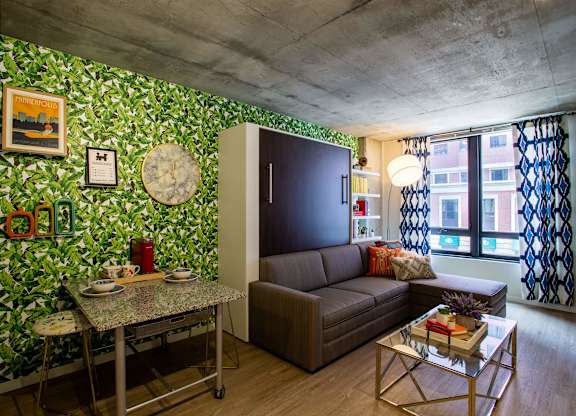 a living room with green wallpaper and a brown couch