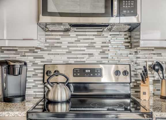 a kitchen with stainless steel appliances and a tea kettle on the stove