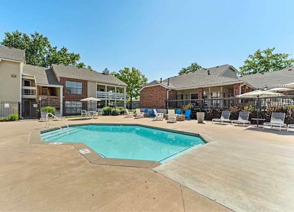 Mission, KS, Garden-Style Apartments Near Downtown Kansas City - Silverwood Apartments - A Swimming Pool Surrounded by Lounge Chairs and Apartment Buildings.