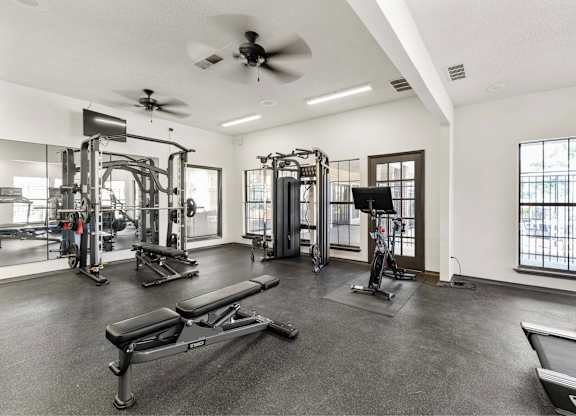 A spacious gym with a variety of equipment including treadmills, weights, and a bench press.
