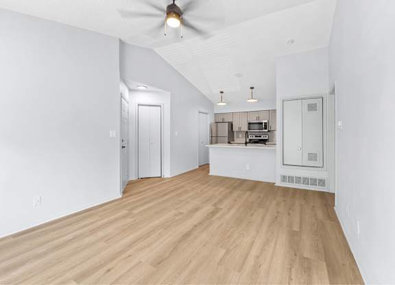 A room with a ceiling fan and a kitchenette.