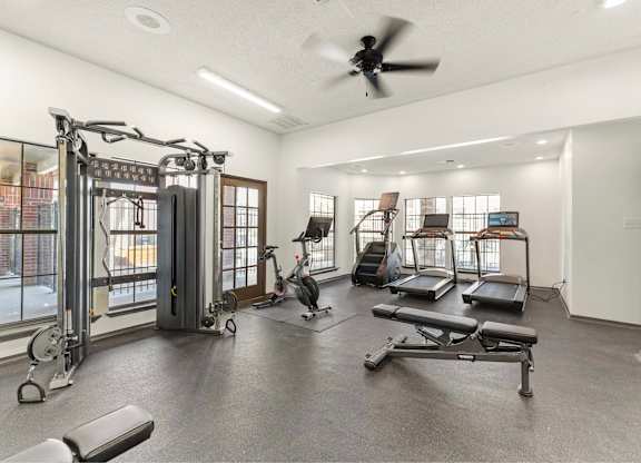 A spacious gym with a variety of equipment including treadmills, weights, and a rowing machine.