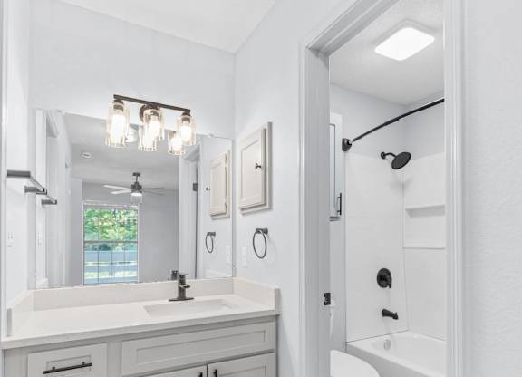 A white bathroom with a sink, mirror, and toilet.