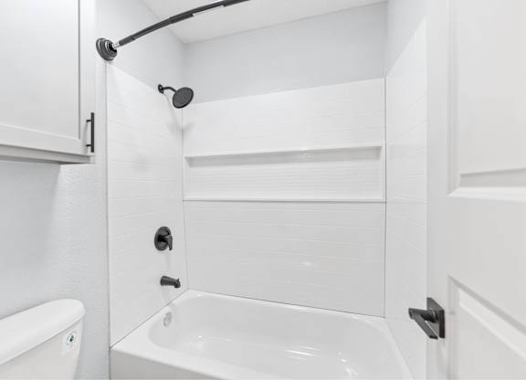 A white bathroom with a tub, shower, and toilet.