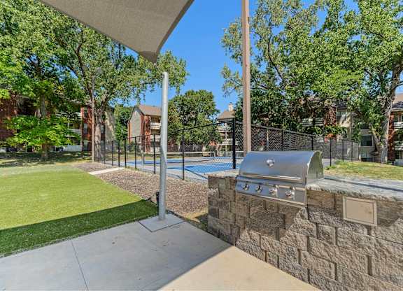 2-Bedroom Garden-Style Apartments in Mission, KS - Silverwood Apartments - An Outdoor Area Featuring a Fenced Sports Court Surrounded by Green Space.