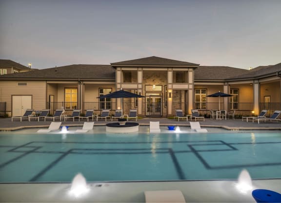 a large pool with chairs and umbrellas at dusk