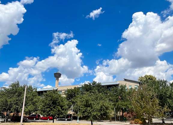 a city with a blue sky with clouds and a building with a tower