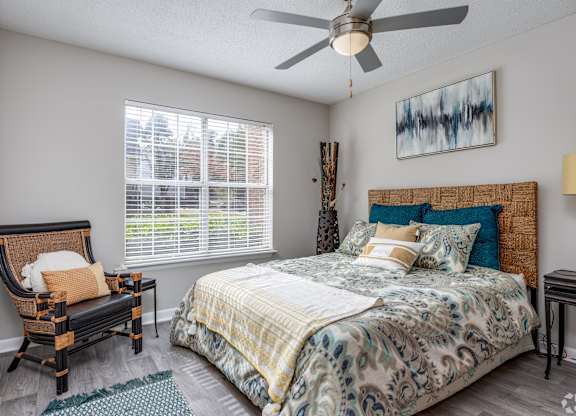 A bedroom with a bed, chair, and a painting on the wall.