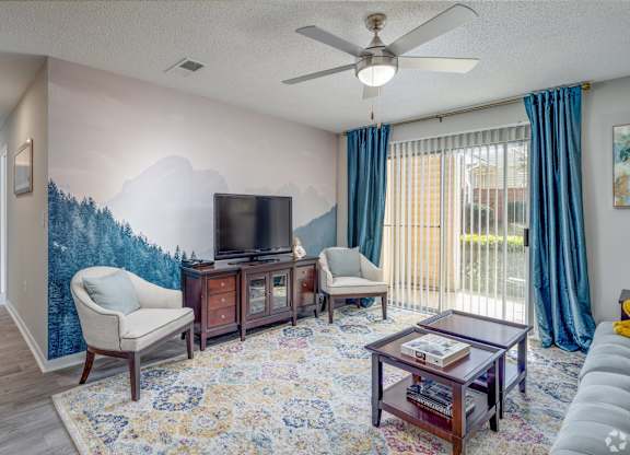 A living room with a television, two chairs, a coffee table, and a rug.