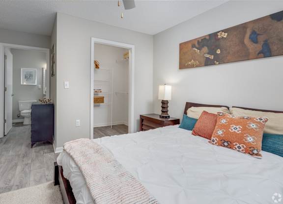 A bedroom with a bed, a nightstand, and a painting on the wall.