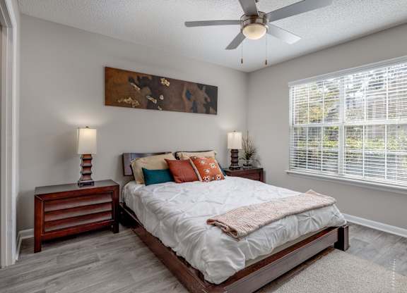 A bedroom with a bed, nightstand, and a painting on the wall.