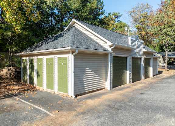 A small house with a grey roof and green doors.