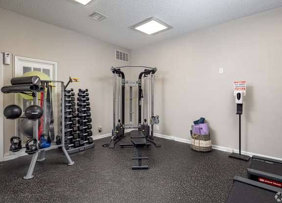 A gym room with a variety of equipment including weights and cardio machines.