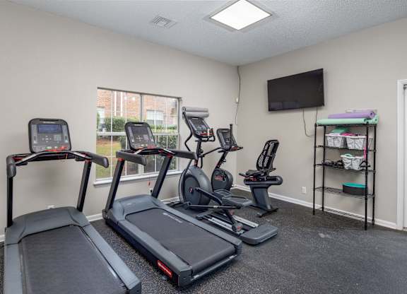 A room with a treadmill, elliptical trainer, and stationary bike.