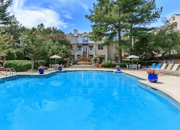 Waters Edge at Harbison's community swimming pool surrounded by trees and lounge chairs.