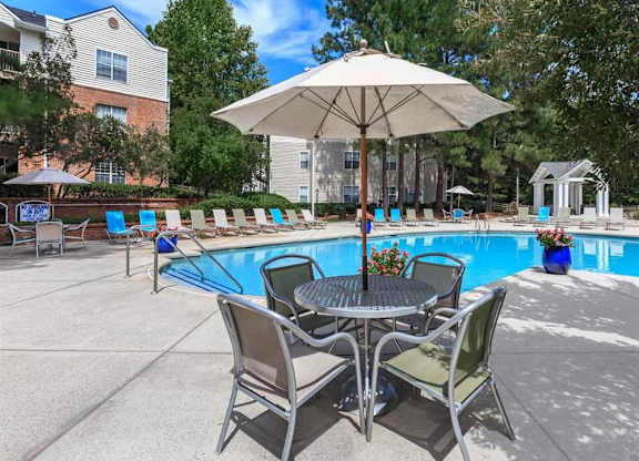 A patio with a table and chairs and a pool.