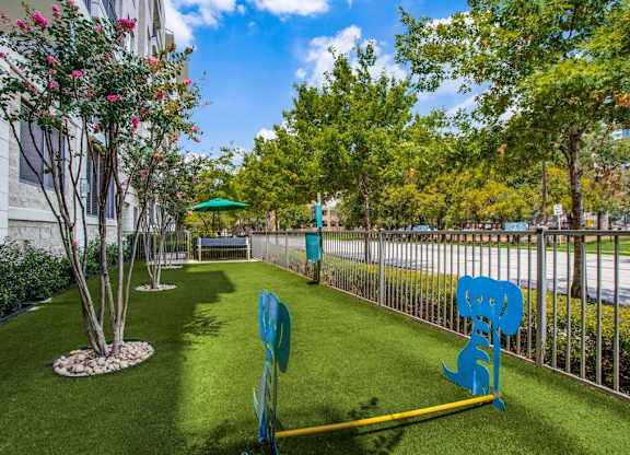 A blue sculpture of a cat is on a green lawn.