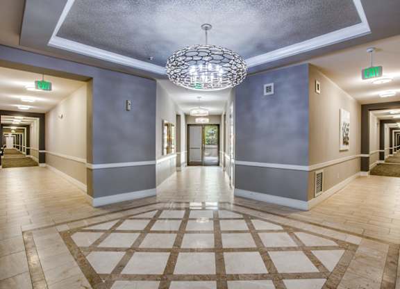 A hallway with a chandelier and a rug on the floor.