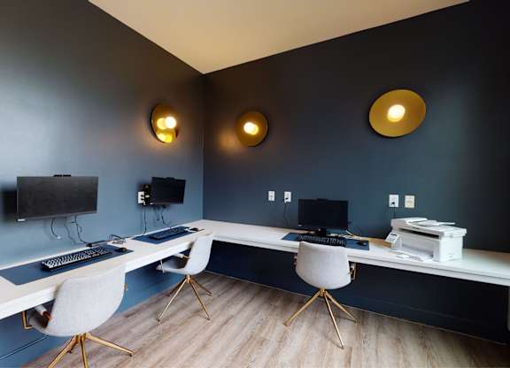 A room with a desk, chairs, and a television.