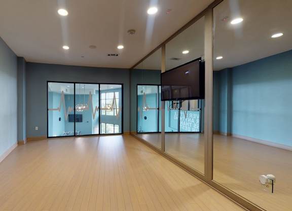 A spacious room with wooden floors and a television mounted on the wall.