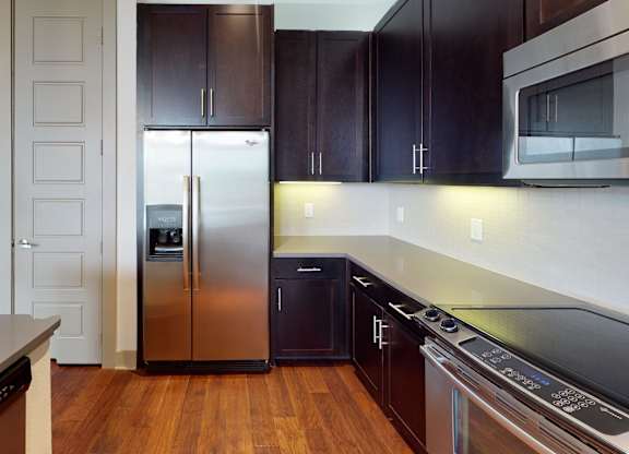 A kitchen with a refrigerator, oven, and microwave.