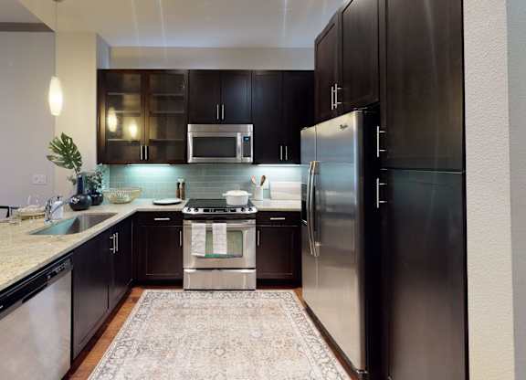 A modern kitchen with a refrigerator, microwave, and oven.