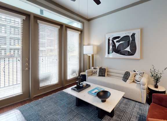 A living room with a white couch, a coffee table, and a painting on the wall