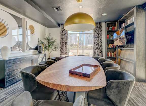 A modern dining room with a round wooden table and grey chairs.