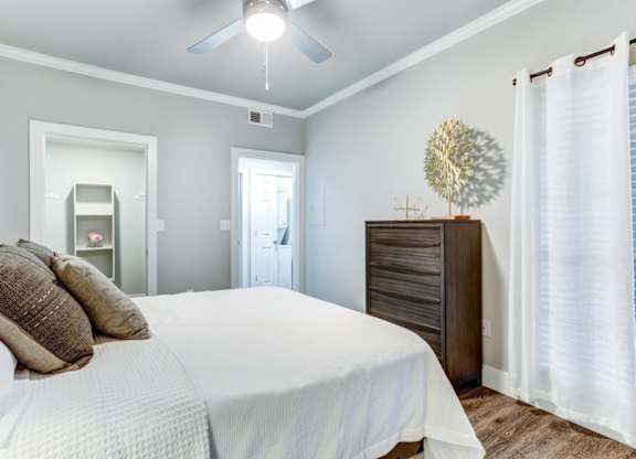 A bedroom with a bed, dresser, and a ceiling fan.
