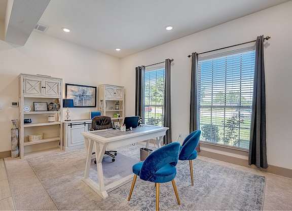 A room with a desk and blue chairs.