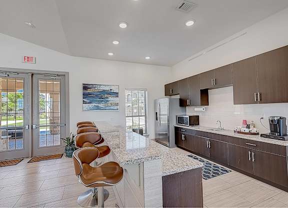 A kitchen with a marble countertop and a view of the outdoors through the window.
