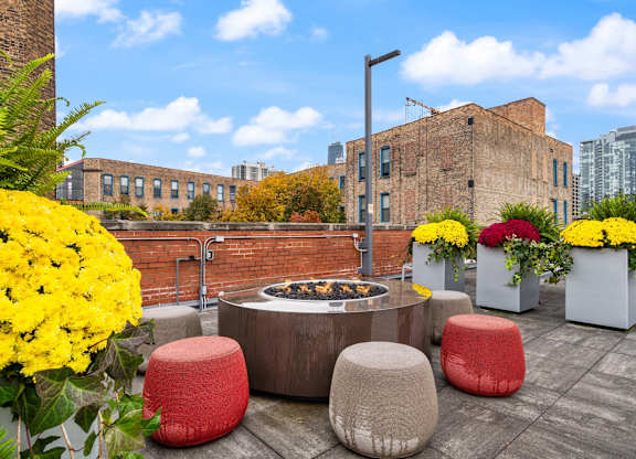 A patio with a fire pit and seating area with flowers.